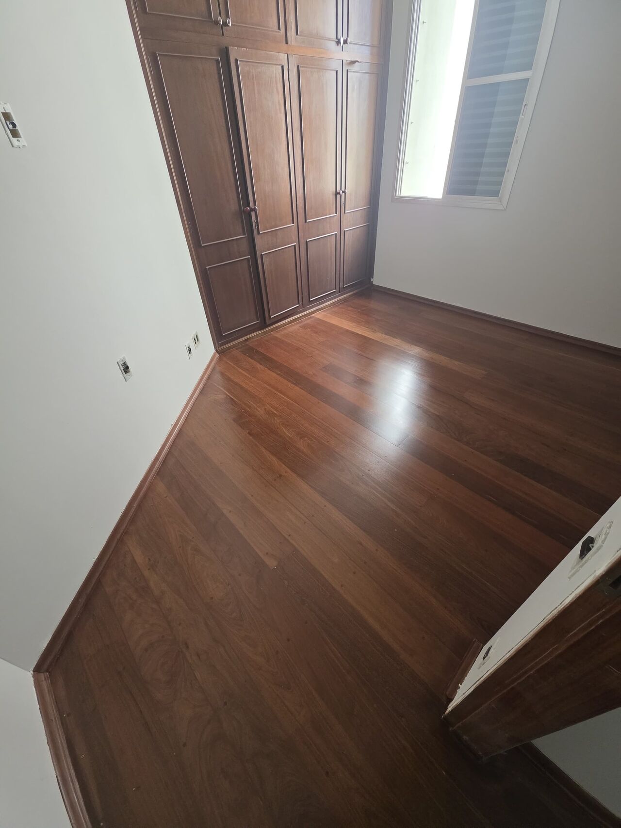 O mesmo quarto com o assoalho restaurado, madeira escura e brilho uniforme