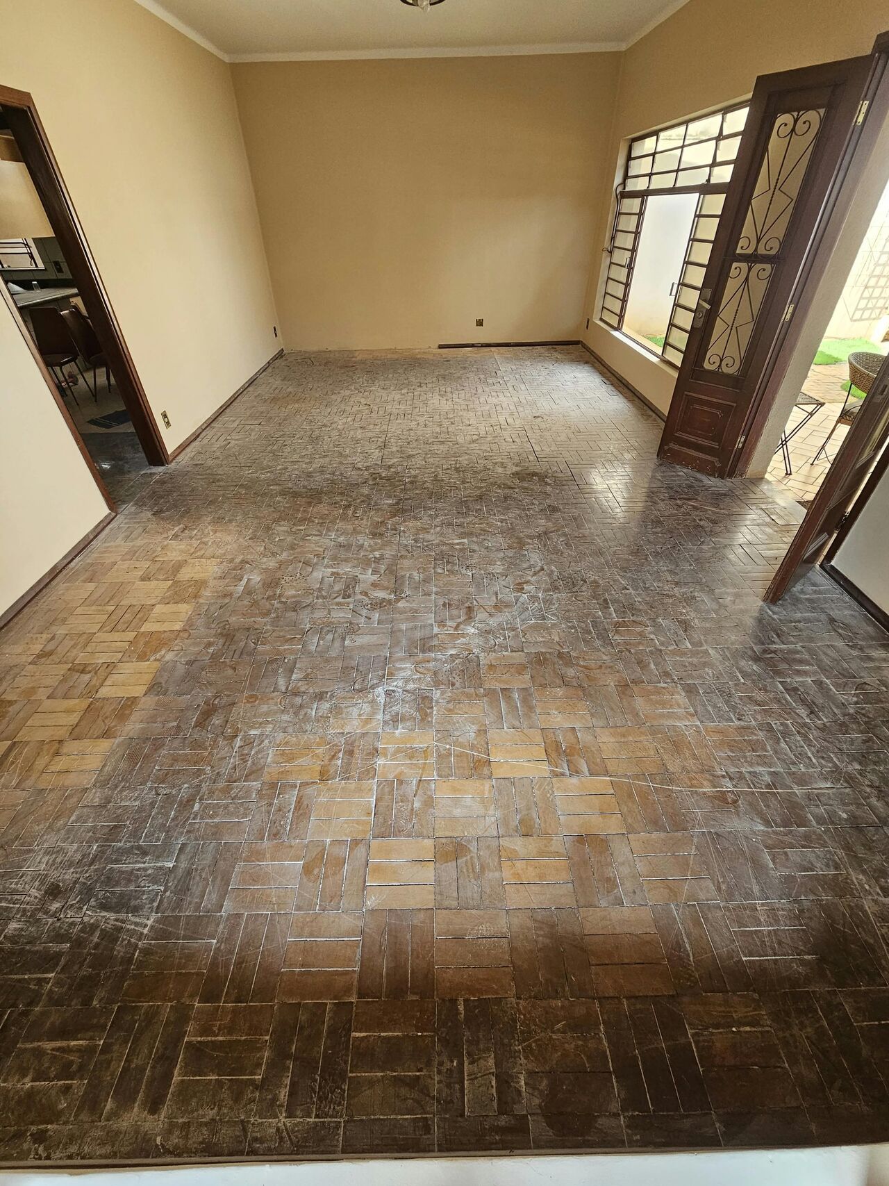 Sala com piso de taco damero desgastado e acinzentado, antes da restauração