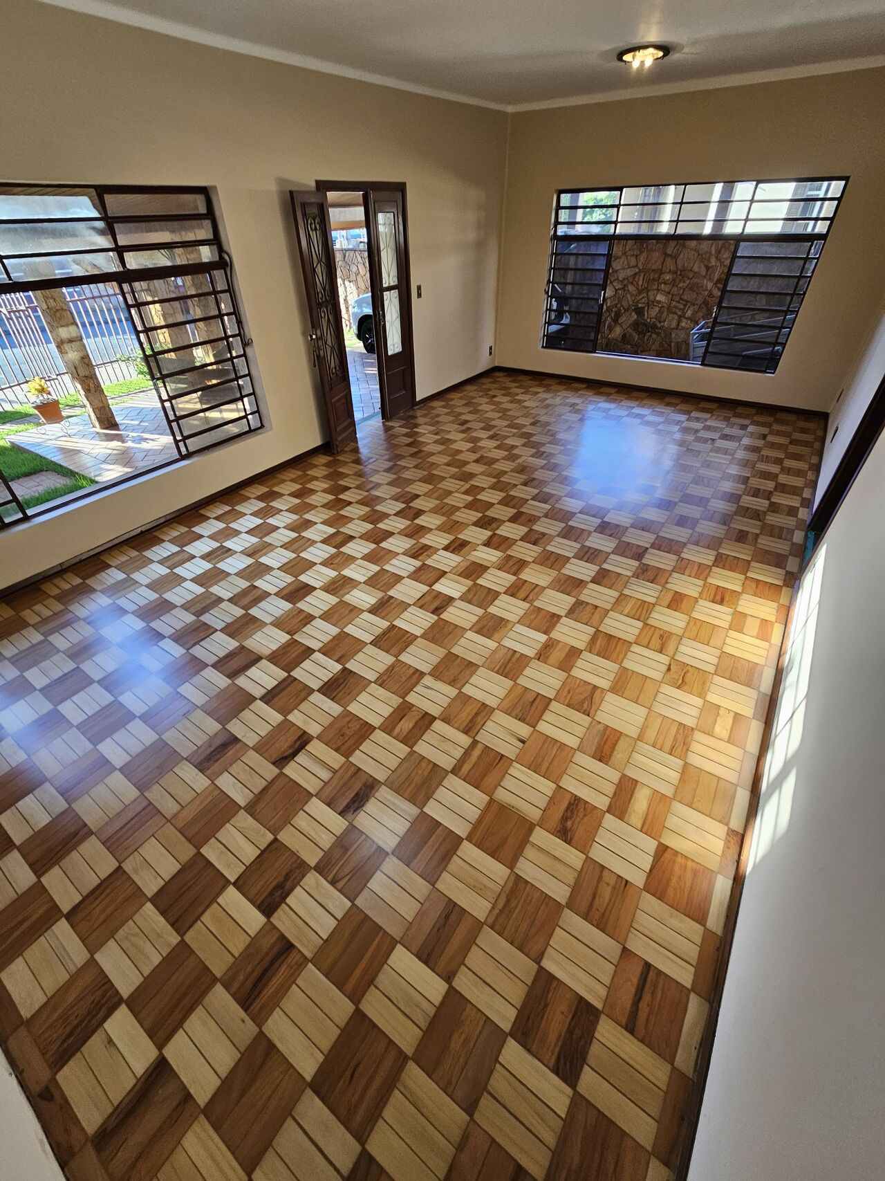A mesma sala com o piso damero restaurado, em dois tons de madeira e verniz Bona semibrilho