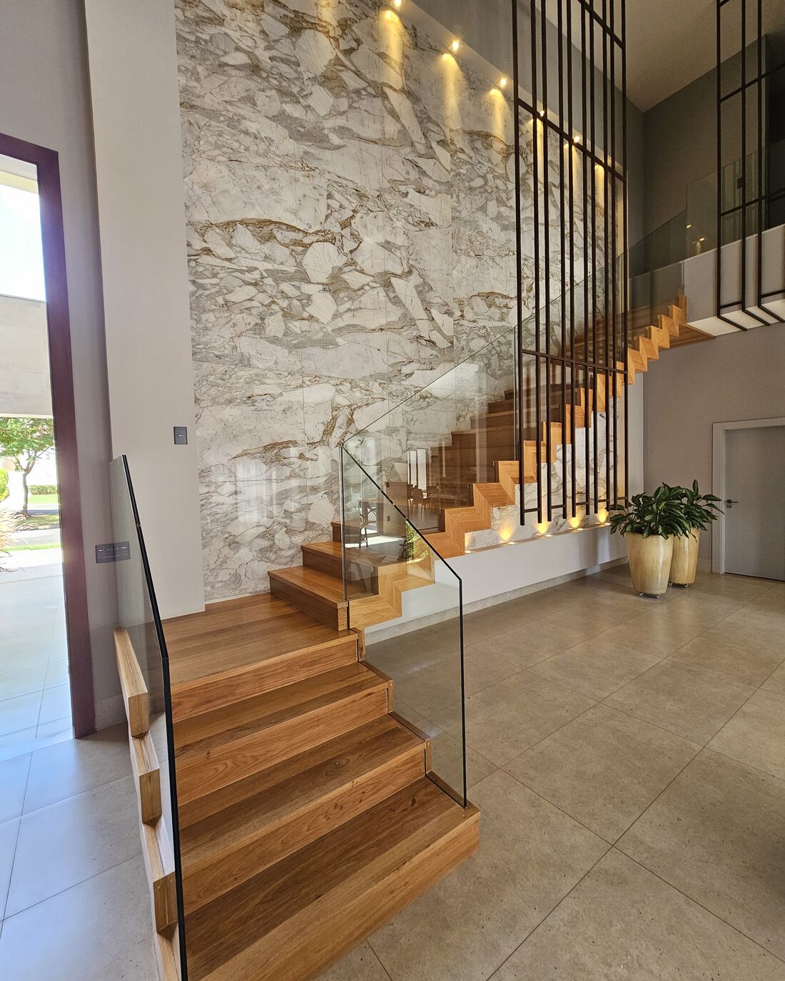 Escada de degraus de madeira com guarda-corpo de vidro em casa de alto padrão